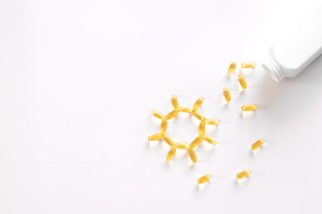 Kapsułki z olejem omega-3 wysypane z butelki na białym tle